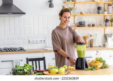 Healthy lifestyle, diet, weight loss concept. Beautiful happy woman cooking healthy food, breakfast from fresh green smoothie standing in the kitchen. Vegetarian, vegan food - Powered by Shutterstock