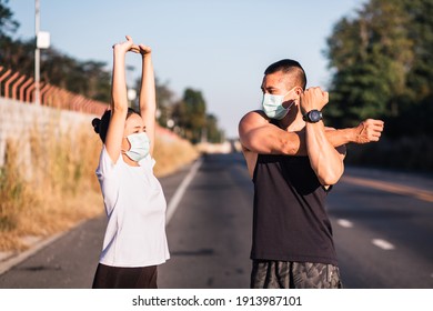 Healthy Lifestyle During Covid-19 Outbreak. Athletic Asian Couple Wearing Face Mask While Relaxing And Stretching Exercise After Working Out On Street Together. Air Pollution 