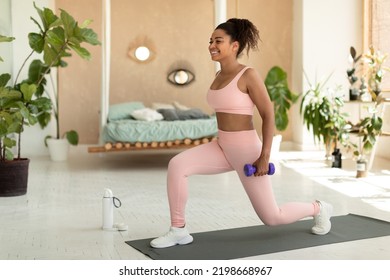 Healthy lifestyle. Fit african american woman doing forward walking lunges with dumbbells, exercising at home. Happy lady training on yoga mat and smiling - Powered by Shutterstock