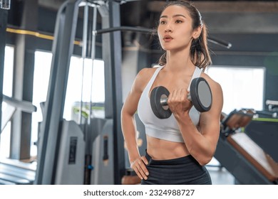 Healthy lifestyle and fitness concept. Asian woman wearing sports bra doing lifting dumbbell weight exercise in sport gym - Powered by Shutterstock