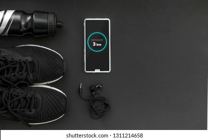 Healthy Lifestyle And Fitness In Sports, Morning Jogging. Sneakers, Headphones And A Water Bottle On A Black Background. Fitness App. Top View And Flatlay