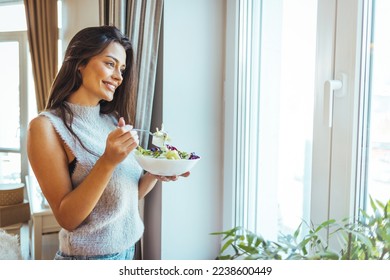 Healthy lifestyle. Good life. Organic food. Vegetables. Close up portrait of happy cute beautiful young woman while she try tasty vegan salad at home. Eating healthy. Beautiful woman eating vegetable 