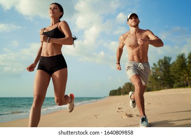 Healthy lifestyle. Jogging outdoors. Young man and woman is running on the sand beach. - Powered by Shutterstock