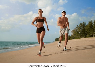 Healthy lifestyle. Jogging outdoors. Young man and woman is running on the sand beach. - Powered by Shutterstock