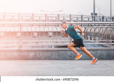 healthy lifestyle middle aged man runner running upstairs on city bridge road. Motion shot
