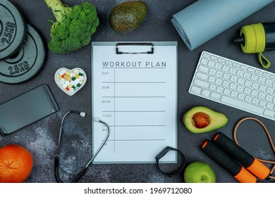 Healthy lifestyle powerlifting concept with grip cast iron olympic weight plates on a cement floor. Clip board with worksheet workout plan tab.