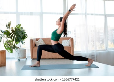 Healthy Lifestyle And Sports Concept. Attractive Hispanic Woman Enjoying Her Morning Yoga Indoors. Warrior Pose