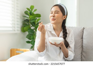 Healthy lifestyle, wellness food asian young woman hand use spoon eat tasty fresh organic yogurt, dairy product in bowl breakfast meal at home. Snack tasty on diet nutrition delicious natural yoghurt