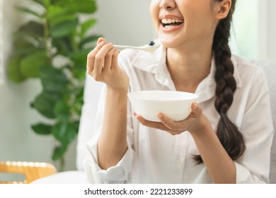 Healthy lifestyle, wellness food asian young woman hand use spoon eat tasty fresh organic yogurt, dairy product in bowl breakfast meal at home. Snack tasty on diet nutrition delicious natural yoghurt