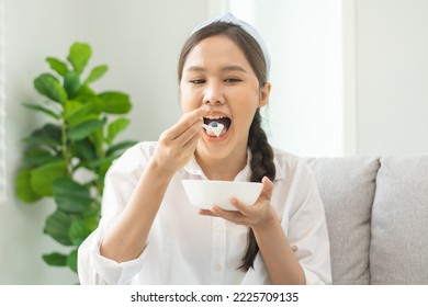 Healthy lifestyle, wellness food asian young woman hand use spoon eat tasty fresh organic yogurt, dairy product in bowl breakfast meal at home. Snack tasty on diet nutrition delicious natural yoghurt