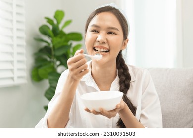 Healthy lifestyle, wellness food asian young woman hand use spoon eat tasty fresh organic yogurt, dairy product in bowl breakfast meal at home. Snack tasty on diet nutrition delicious natural yoghurt