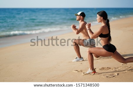 Healthy lifestyle. Young beautiful couple doing sports exercises at the beach.