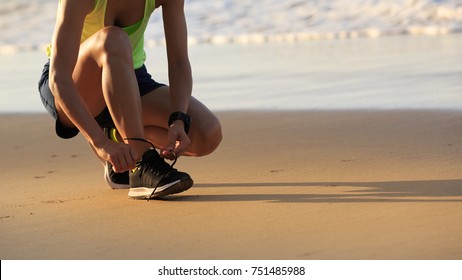 healthy lifestyle young fitness woman runner tying shoelace on beach - Powered by Shutterstock