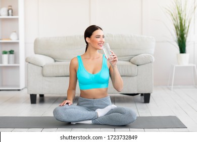 Healthy Lifestyle. Young Woman Drinking Water Sitting In Lotus Position On Yoga Mat At Home - Powered by Shutterstock