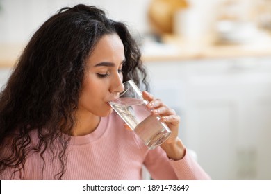 Healthy Liquid. Beautiful Brunette Woman Drinking Mineral Water From Glass In Kitchen, Thirsty Young Lady Enjoying Refreshing Drink At Home, Closeup Portrait With Selective Focus, Free Space