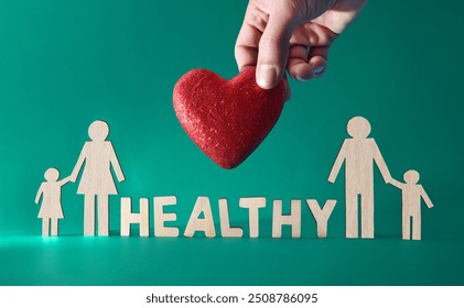 Healthy living for the whole family with family cutouts and letters with message and hand holding red heart on green background. Front view. - Powered by Shutterstock