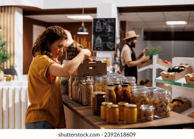 Healthy living woman in zero waste shop looking to buy freshly handpicked apples and other fruits. Customer shopping for chemicals free groceries in local neighborhood store
