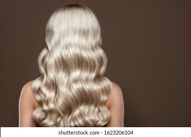  Healthy Long blonde Shiny Wavy hair back view. Volume shampoo. Blond Curly permed Hair.  Beauty salon and hair care concept.