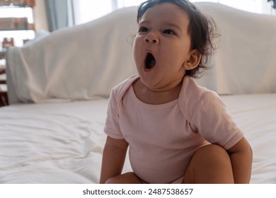 Healthy lovely infant children gape after wake up sitting on bed at home. Toddler innocent daughter wake up yawn mouth relax sitting alone napping in bedtime morning. Childhood open mouth yawn at home - Powered by Shutterstock