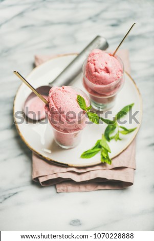 Healthy low calorie summer dessert. Homemade strawberry yogurt ice cream in glasses over light grey marble table background, selective focus. Clean eating, dieting food concept