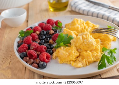 Healthy low carb breakfast plate with homemade scrambled eggs, fresh berries and nuts