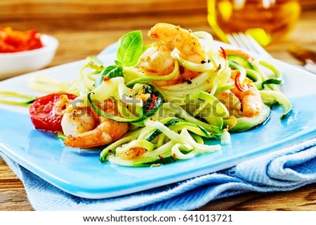 Healthy low carbohydrate seafood starter with a fresh raw vegetable salad and grilled spicy queen prawn tails dressed in olive oil served on a blue platter