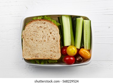 Healthy Lunch Box With Sandwich And Fresh Vegetables On White Wooden Background. From Top View