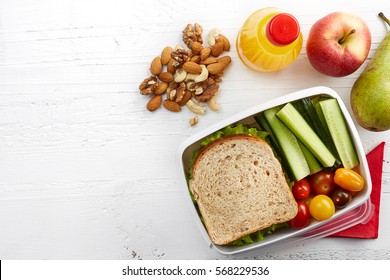 Healthy Lunch Box With Sandwich, Fresh Vegetables And Fruits On White Wooden Background. From Top View