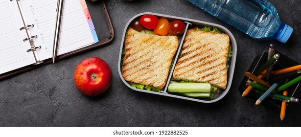 Healthy Lunch Box With Sandwich And Vegetables, Apple And Water Bottle On Office Table. Top View Flat Lay