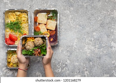 Healthy lunch menu. Woman holding foil container with take away food, top view, copy space