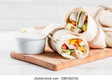 Healthy lunch snack. Stack of mexican street food fajita tortilla wraps with grilled buffalo chicken fillet and fresh vegetables, light grey background copy space