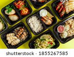 Healthy lunch at the workplace. Pick up food in black containers with Cutlery on a yellow background