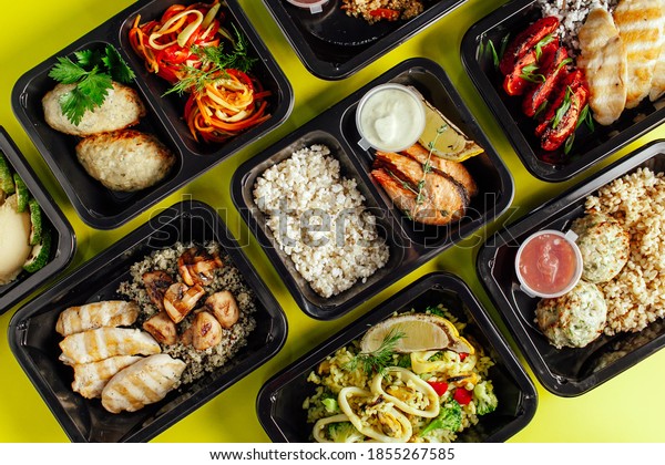 Healthy lunch at the\
workplace. Pick up food in black containers with Cutlery on a\
yellow background