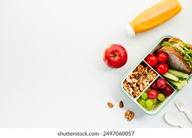 Healthy lunchbox with sandwich, nuts, cherry tomatoes, cucumber slices, grapes, apple, and orange juice. Perfect for nutrition, wellness, and healthy lifestyle themes - Powered by Shutterstock