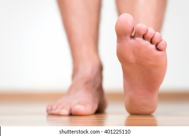 Healthy male feet stepping over home-like background