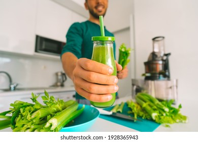 Healthy man making fresh detox homemade celery juice in juicer machine at home and holding a glass bottle of celery juice. Healthy detox diet