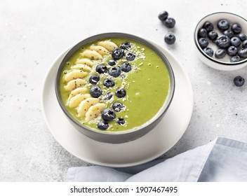 Healthy Matcha Green Tea Smoothie Bowl Topped With Banana, Blueberry, Chia Seeds And Coconut. Vegan Raw Food. Gray Background. Flat Lay. Close-up