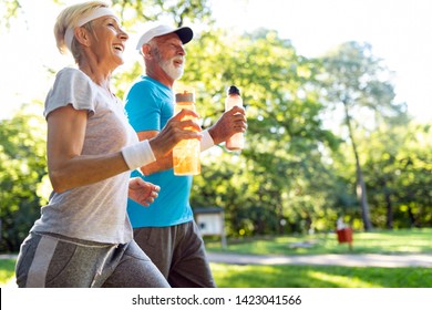Healthy mature couple jogging in a park at early morning with sunrise