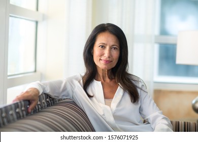 Healthy mature hispanic woman sitting on a sofa.