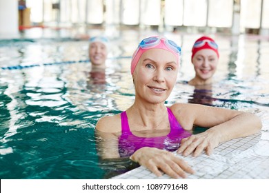 Healthy mature sportswoman and her friends in swimwear spending time in swimming-pool - Powered by Shutterstock