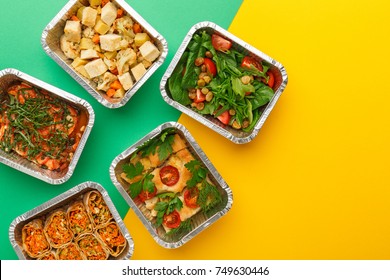 Healthy meals delivery. Casserole, vegetarian rolls, fresh and baked vegetables salads in foil take away boxes on abstract bright background. Eating right concept, copy space, top view.