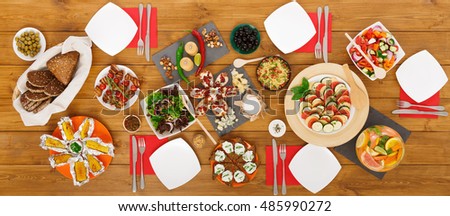 Healthy meals at festive table served for party. Authentic celebration with organic food on wooden table top view. Ratatoille, cheese, corn and chicken barbecue, sandwiches with mojito and lemonade