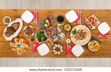 Healthy meals at festive table served for party. Authentic celebration with organic food on wooden table top view. Ratatoille, cheese, corn and chicken barbecue, sandwiches with mojito and lemonade
