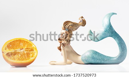 Healthy mermaid looks at orange half