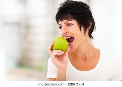 healthy middle aged woman eating a green apple