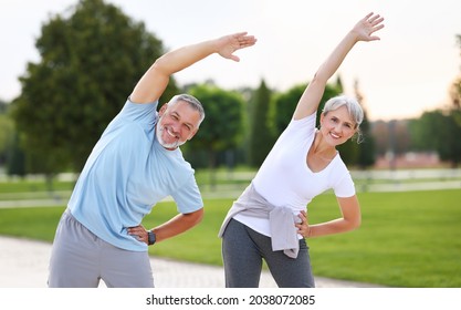 Healthy Mind And Body. Full Length Shot Of Happy Smiling Mature Family Man And Woman In Sportswear Stretching Arms While Warming Up Together Outdoors In Park Lane On Sunny Morning. Active Lifestyle