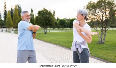 Healthy Mind And Body. Full Length Shot Of Happy Smiling Mature Family Man And Woman In Sportswear Stretching Arms While Warming Up Together Outdoors In Park Lane On Sunny Morning. Active Lifestyle