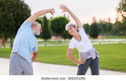 Healthy mind and body. Full length shot of happy smiling mature family man and woman in sportswear stretching arms while warming up together outdoors in park lane on sunny morning. Active lifestyle - Shutterstock ID 2042351396