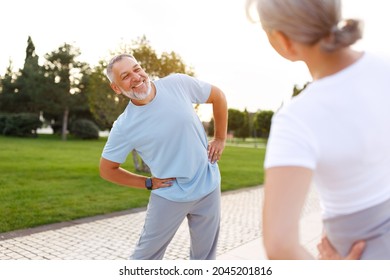 Healthy Mind And Body. Full Length Shot Of Happy Smiling Mature Family Man And Woman In Sportswear Stretching Arms While Warming Up Together Outdoors In Park On Sunny Morning. Active Lifestyle