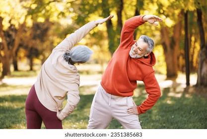 Healthy mind and body. Full length shot of happy smiling mature family man and woman in sportswear stretching body while warming up together outdoors in park lane on autumn morning. Active lifestyle
 - Powered by Shutterstock